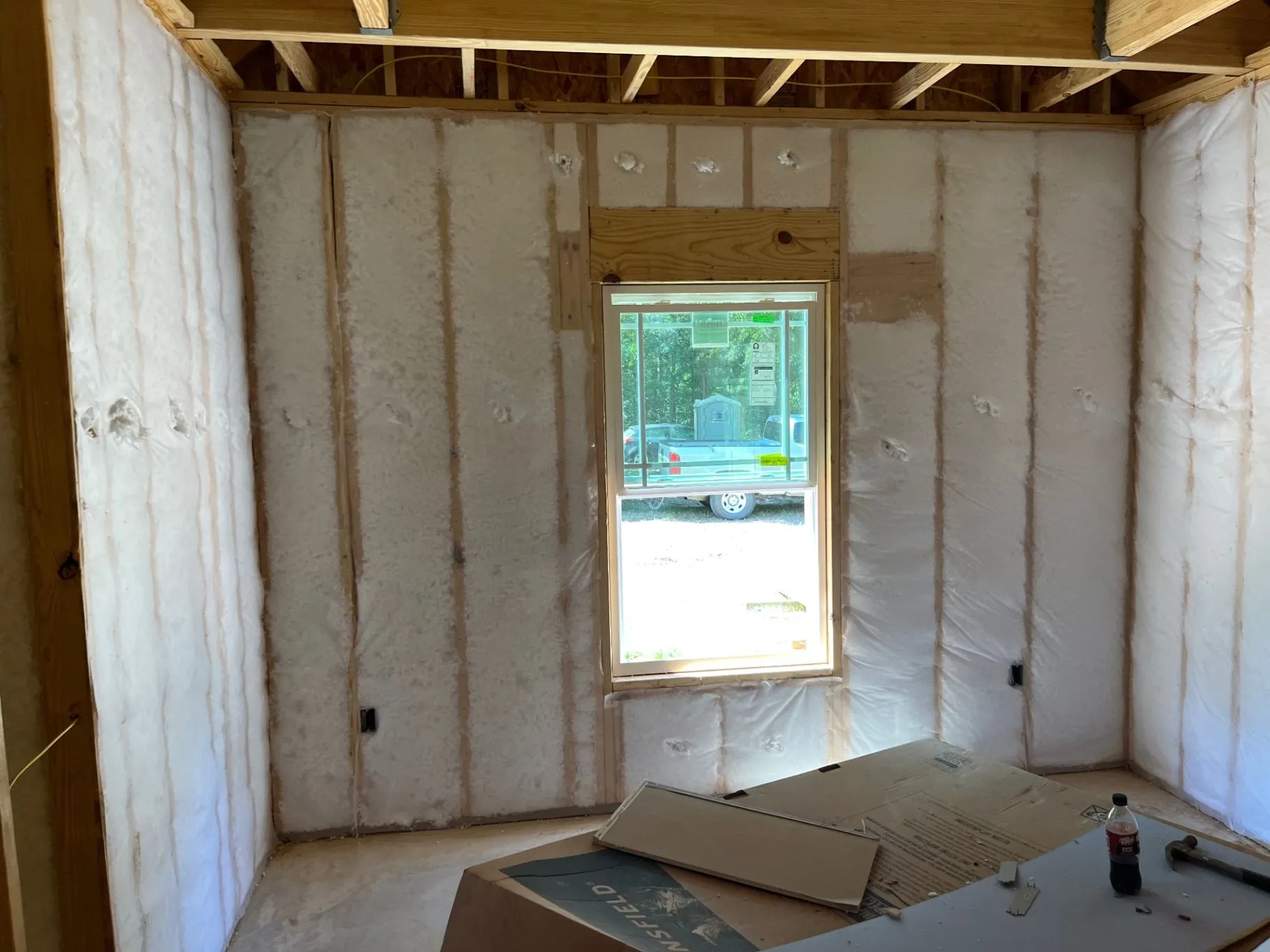 Net-and-blow wall insulation installed around a window in open wood-framed wall cavities